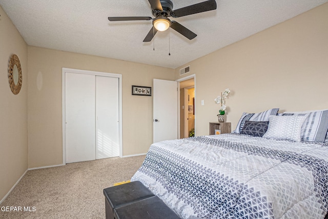 bedroom with ceiling fan, a closet, carpet, and a textured ceiling