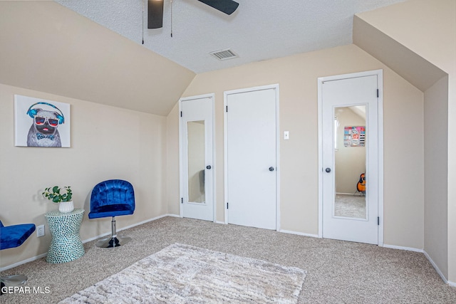 interior space with carpet, ceiling fan, lofted ceiling, and a textured ceiling