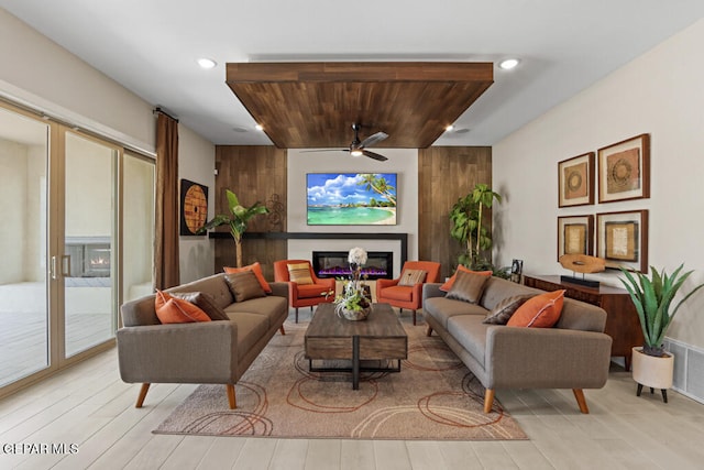 living room with a healthy amount of sunlight, ceiling fan, wood ceiling, and wood walls