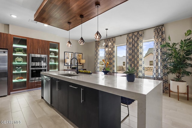 kitchen featuring appliances with stainless steel finishes, a kitchen island with sink, pendant lighting, and wood ceiling