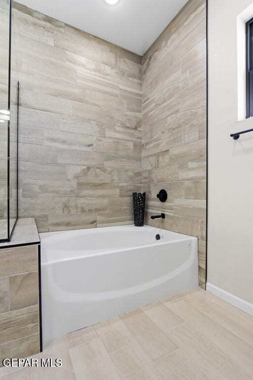 bathroom with tile patterned floors and a bath