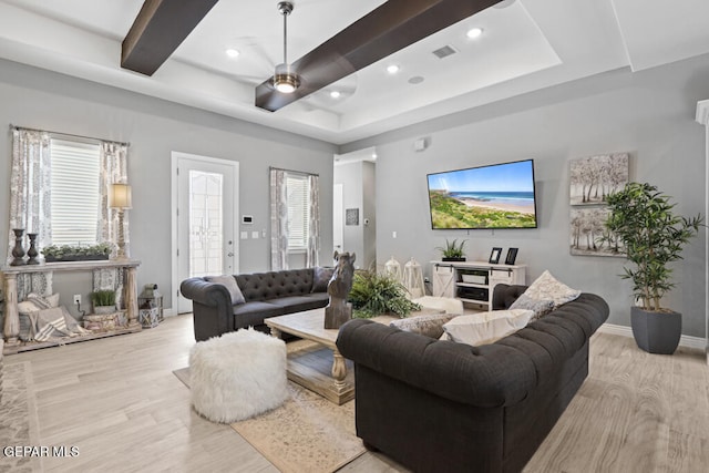 living room featuring light wood-type flooring, a tray ceiling, and ceiling fan