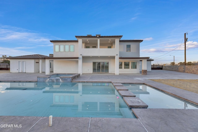 rear view of property featuring a swimming pool with hot tub and a patio