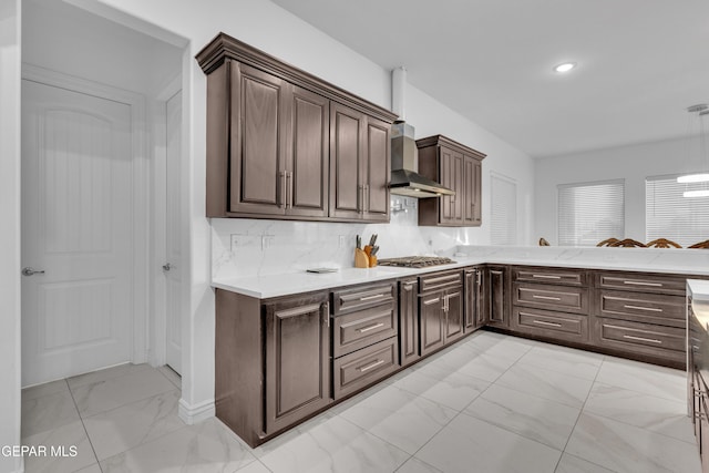 kitchen with wall chimney range hood, decorative backsplash, dark brown cabinets, and stainless steel gas stovetop