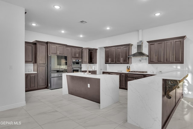 kitchen featuring dark brown cabinetry, sink, a breakfast bar area, stainless steel appliances, and wall chimney range hood