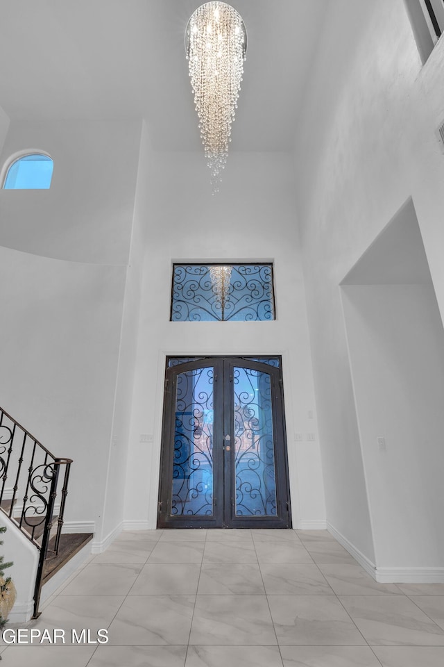 foyer with an inviting chandelier, french doors, and a high ceiling