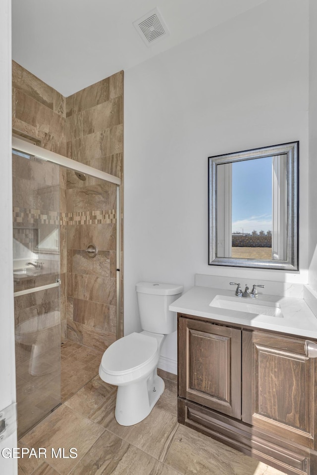 bathroom featuring an enclosed shower, vanity, and toilet