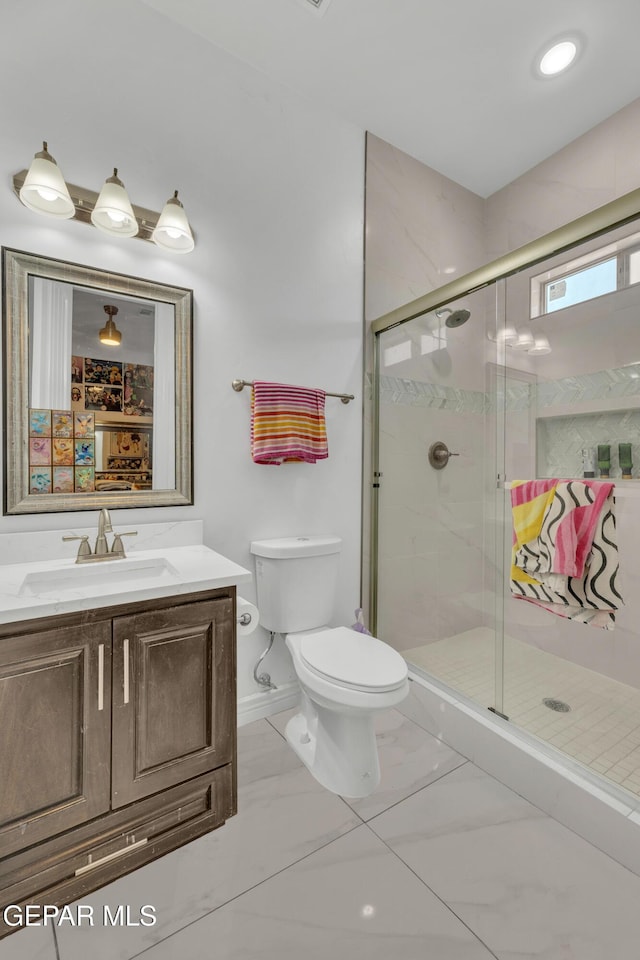 bathroom featuring a shower with door, vanity, and toilet