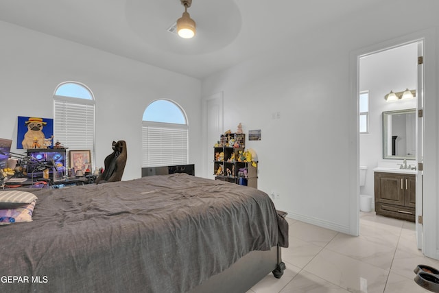 bedroom featuring ensuite bathroom, sink, and ceiling fan