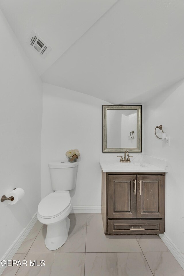 bathroom featuring lofted ceiling, vanity, and toilet