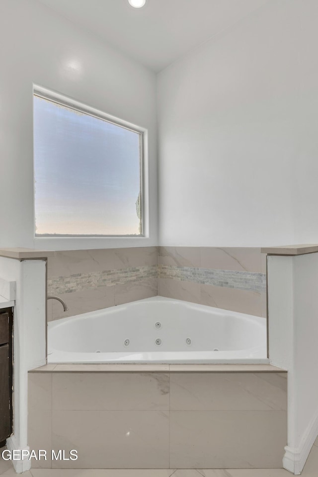 bathroom featuring a relaxing tiled tub and vanity