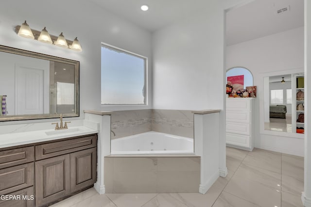 bathroom with vanity and tiled tub