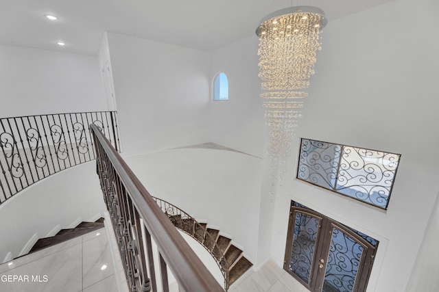 staircase with tile patterned flooring, a notable chandelier, and french doors