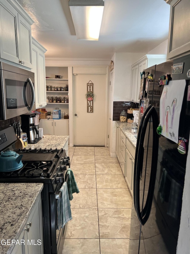 kitchen featuring black appliances, gray cabinetry, light stone countertops, and light tile patterned floors