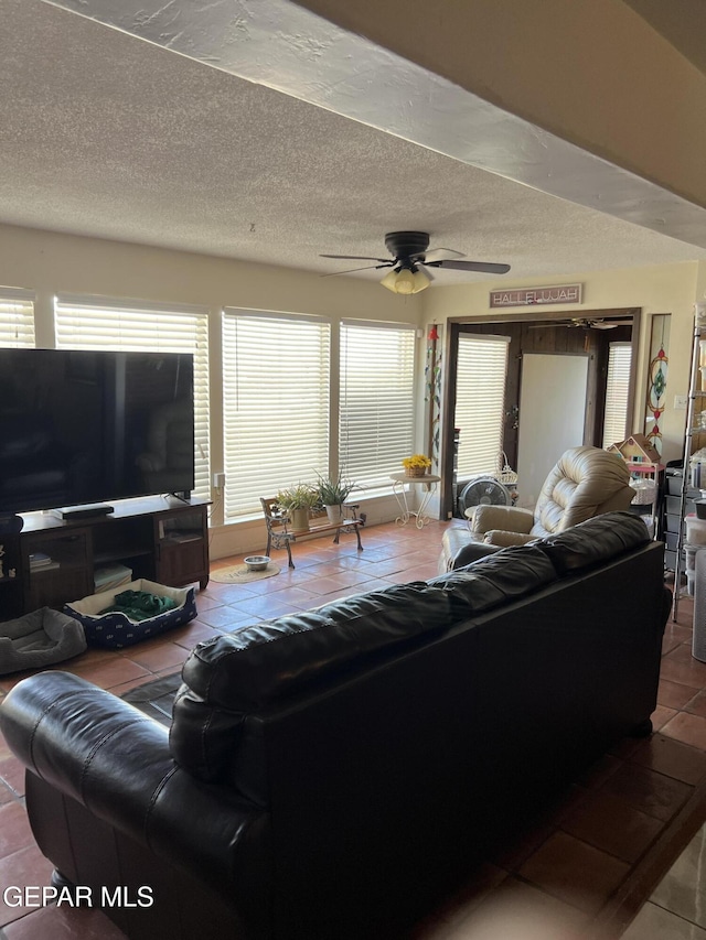 living room with ceiling fan, tile patterned flooring, and a textured ceiling