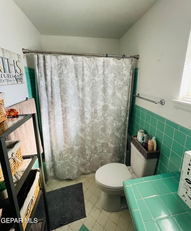 bathroom with tile patterned floors, toilet, tile walls, and walk in shower