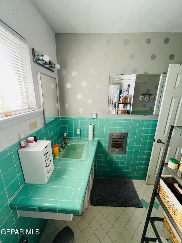 bathroom featuring heating unit, tile walls, and sink