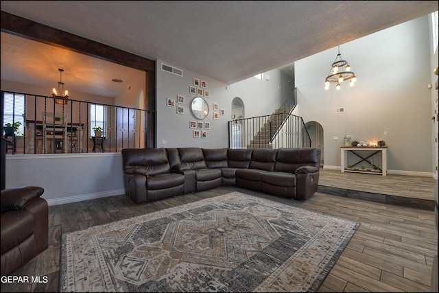 living room with hardwood / wood-style floors, beam ceiling, and an inviting chandelier