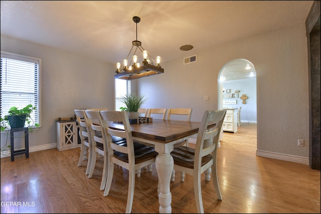 dining room with light wood-type flooring and an inviting chandelier