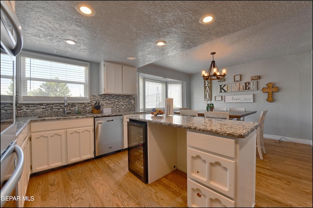 kitchen featuring white cabinets, dishwasher, pendant lighting, and sink