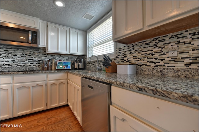 kitchen with tasteful backsplash, white cabinetry, sink, and appliances with stainless steel finishes