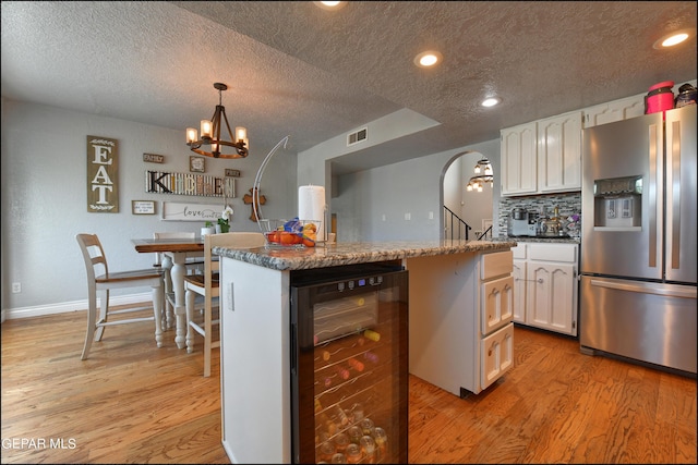 kitchen with a kitchen island, beverage cooler, light hardwood / wood-style flooring, stainless steel fridge with ice dispenser, and white cabinetry