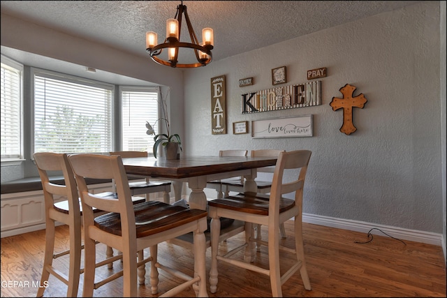 dining room featuring hardwood / wood-style flooring, a textured ceiling, and an inviting chandelier