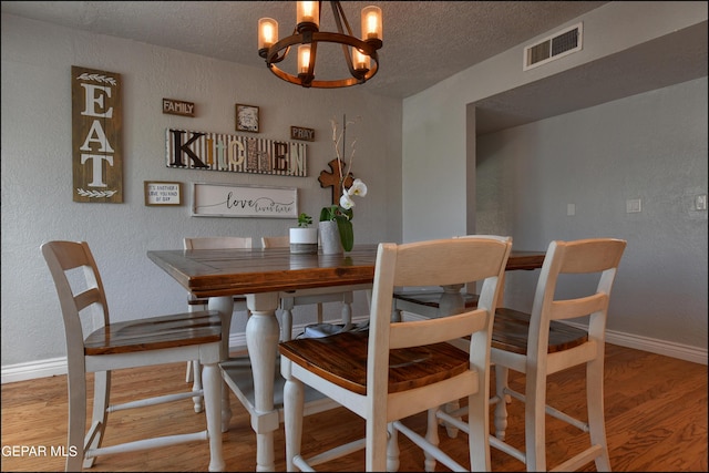 dining room featuring hardwood / wood-style floors, a textured ceiling, and a chandelier