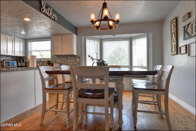 dining room with hardwood / wood-style floors, a textured ceiling, and a chandelier