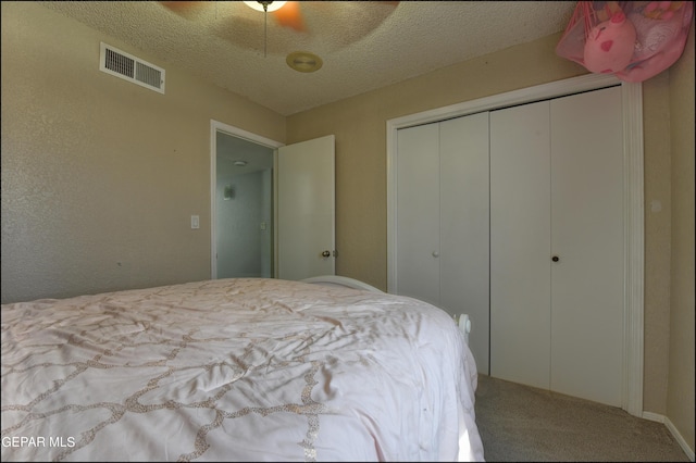 carpeted bedroom featuring ceiling fan, a closet, and a textured ceiling