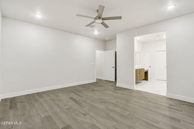 empty room with ceiling fan and light hardwood / wood-style flooring