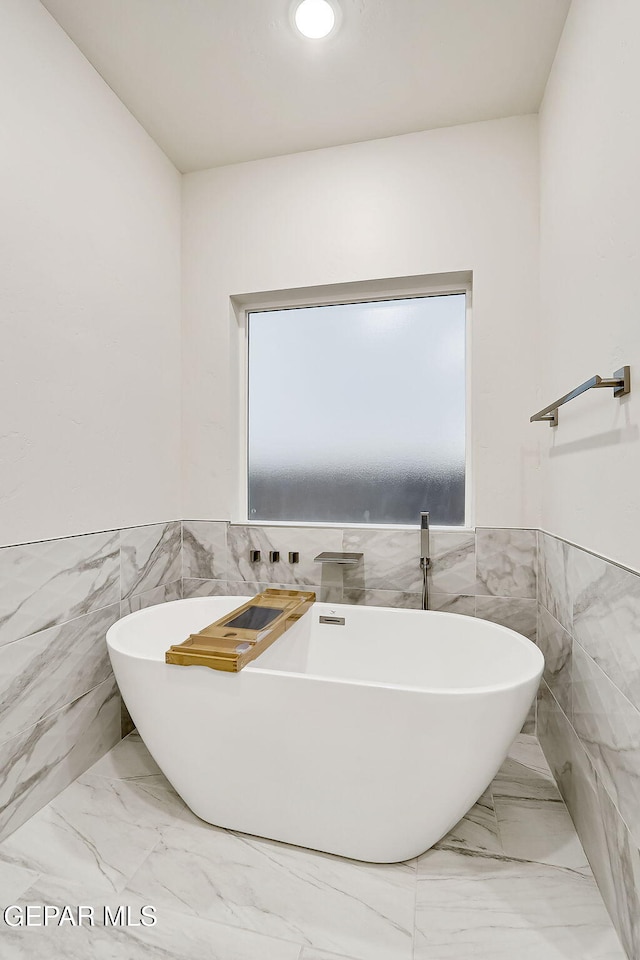 bathroom with a bath and tile walls