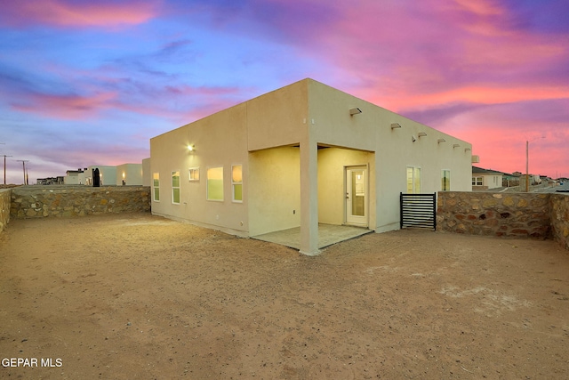 back house at dusk featuring a patio