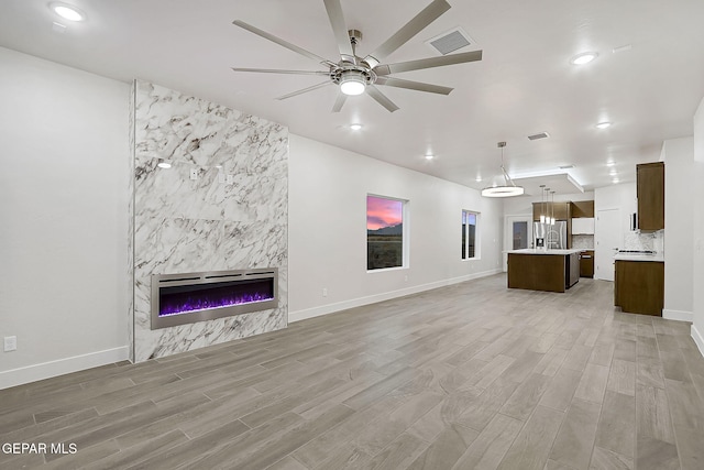 unfurnished living room with hardwood / wood-style flooring, ceiling fan, heating unit, and a fireplace