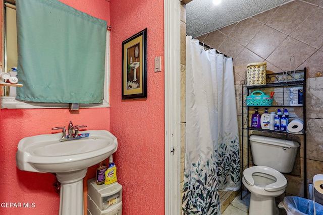 bathroom featuring a shower with shower curtain, a textured ceiling, and toilet