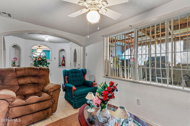 living room featuring ceiling fan, light tile patterned floors, and a textured ceiling