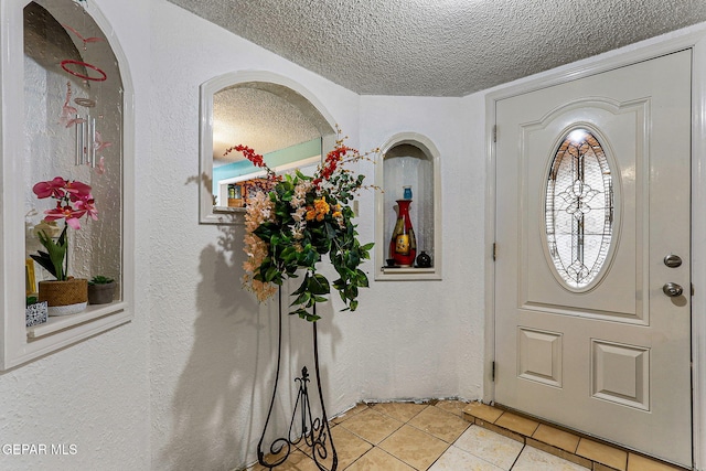 entrance foyer featuring a textured ceiling and light tile patterned flooring