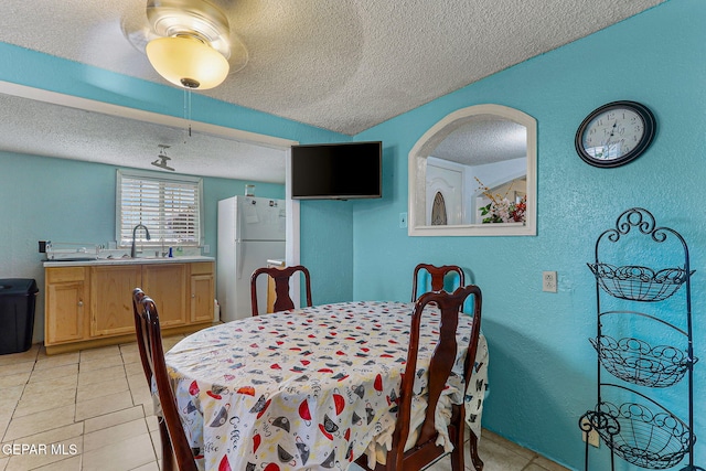 tiled dining room featuring sink and a textured ceiling