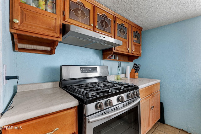 kitchen featuring stainless steel gas stove, light tile patterned floors, and a textured ceiling