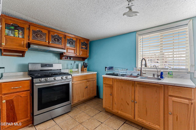 kitchen with stainless steel range, light tile patterned floors, a textured ceiling, and sink