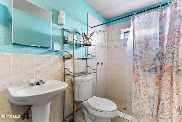 bathroom with tile walls, toilet, a textured ceiling, and walk in shower