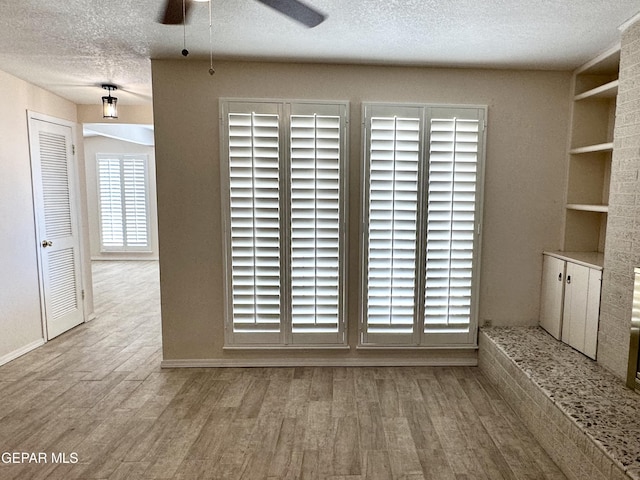 interior space with light hardwood / wood-style floors, built in features, and a textured ceiling