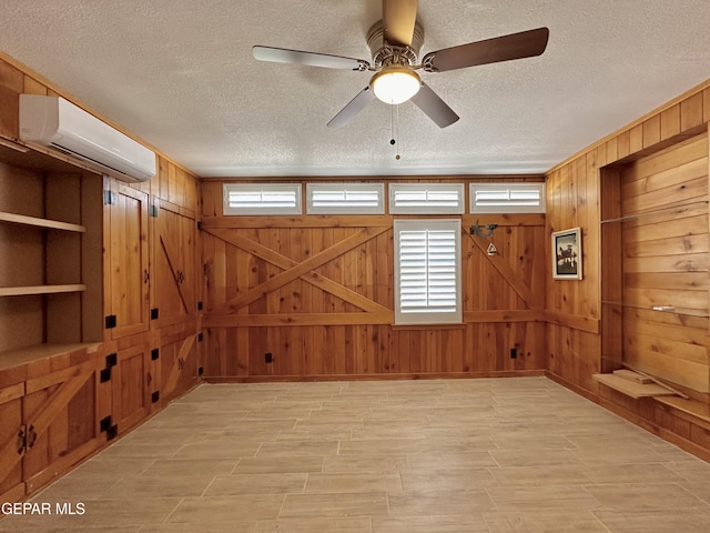 spare room with a wall mounted air conditioner, built in shelves, a textured ceiling, and wood walls