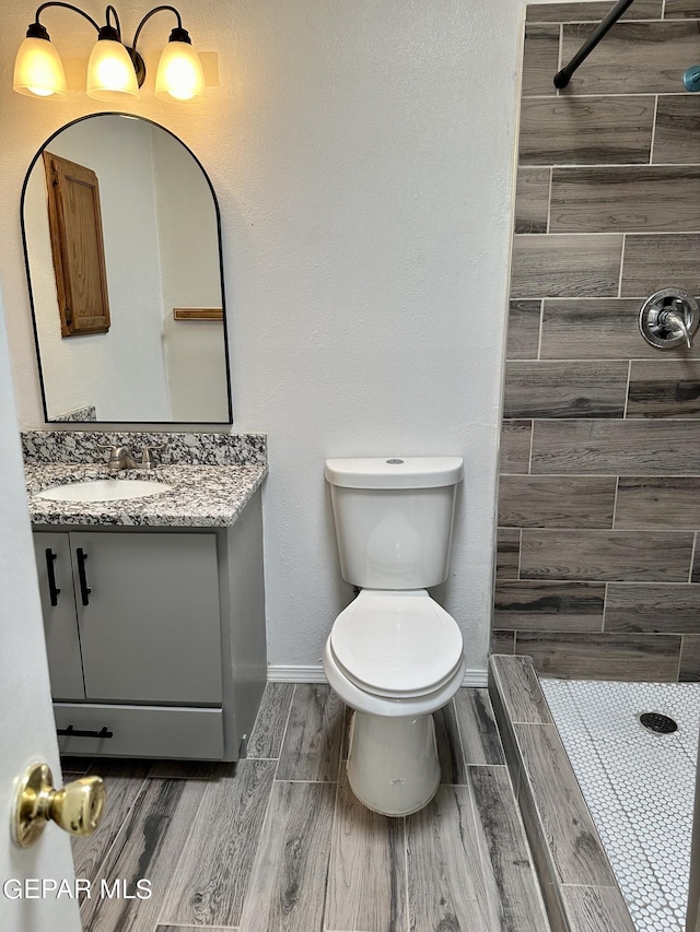 bathroom featuring vanity, toilet, and a tile shower