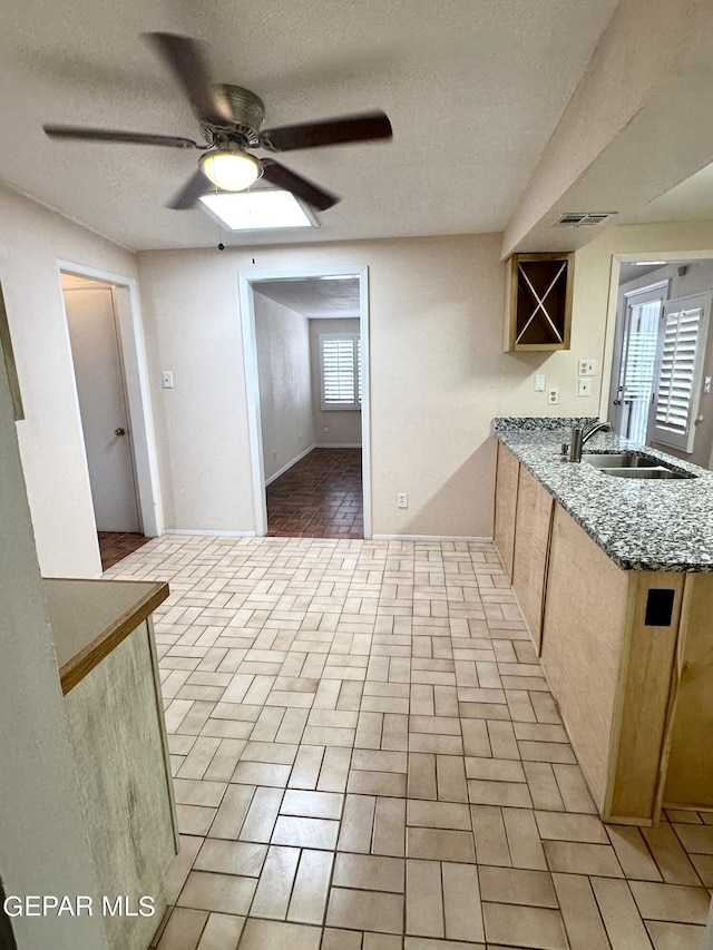 kitchen featuring ceiling fan, sink, and a textured ceiling