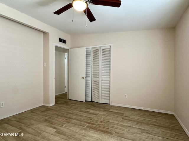 unfurnished bedroom with ceiling fan, light wood-type flooring, and a closet