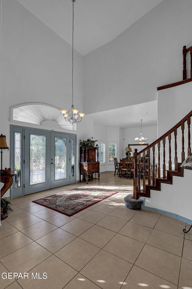 tiled foyer with a towering ceiling and a chandelier