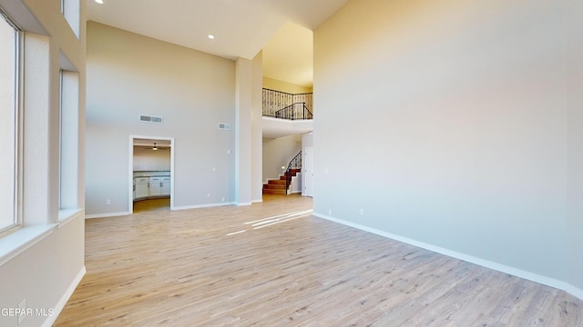 unfurnished living room featuring light hardwood / wood-style flooring and a towering ceiling