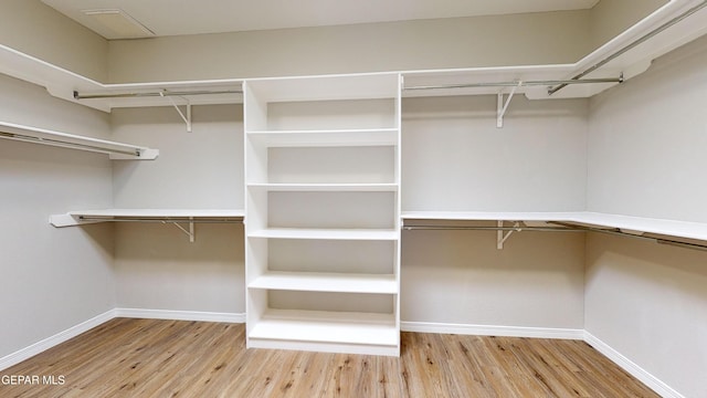 walk in closet with light hardwood / wood-style floors