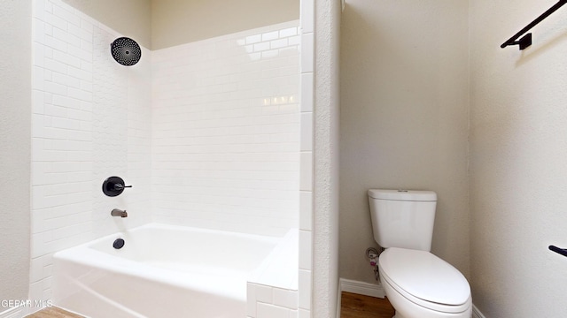 bathroom featuring hardwood / wood-style floors, tiled shower / bath, and toilet